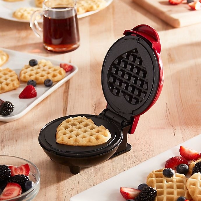 the red waffle maker with a heart-shaped waffle inside