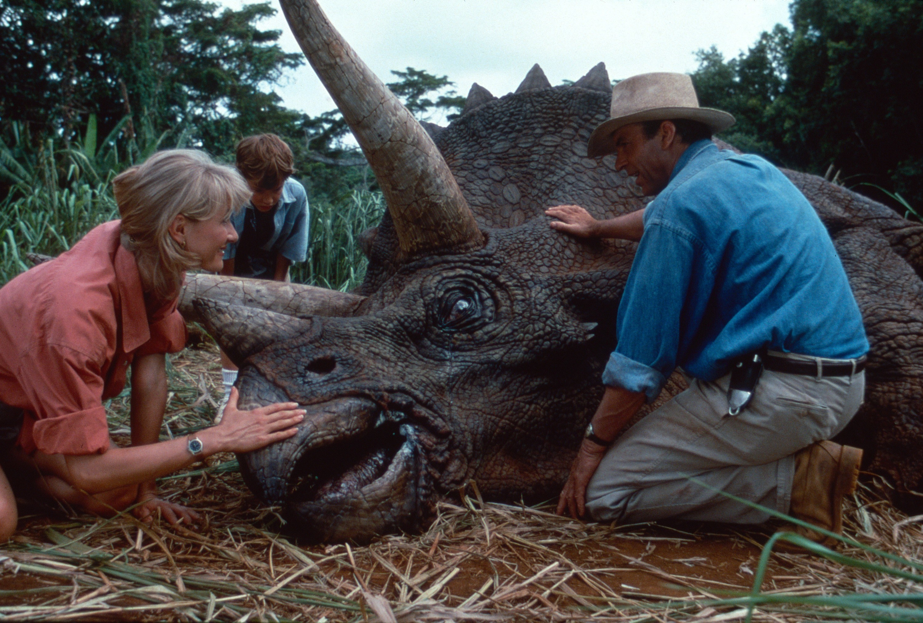 Scientists kneel down with a pained dinosaur