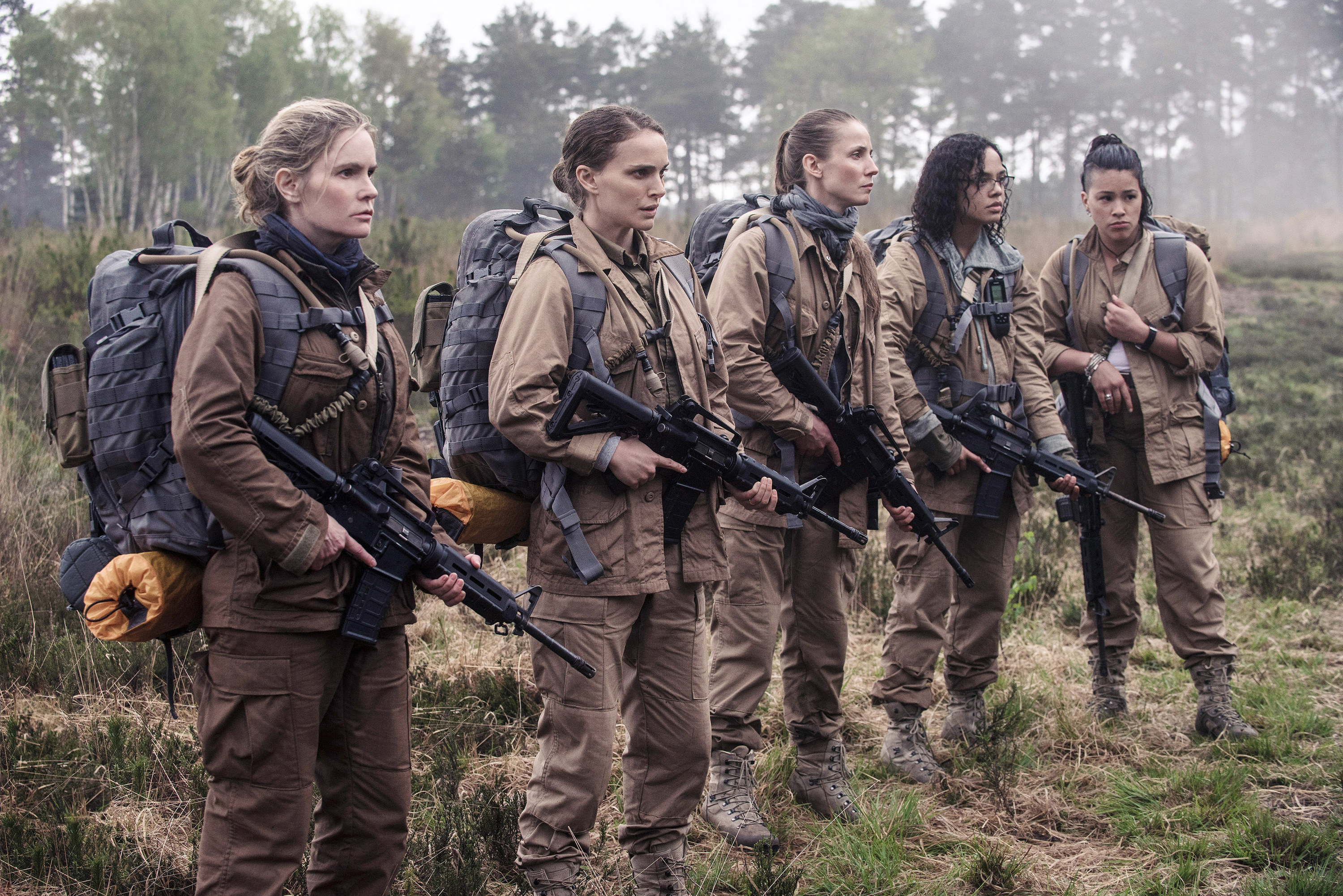 Five women in uniform holding guns and wearing large backpacks