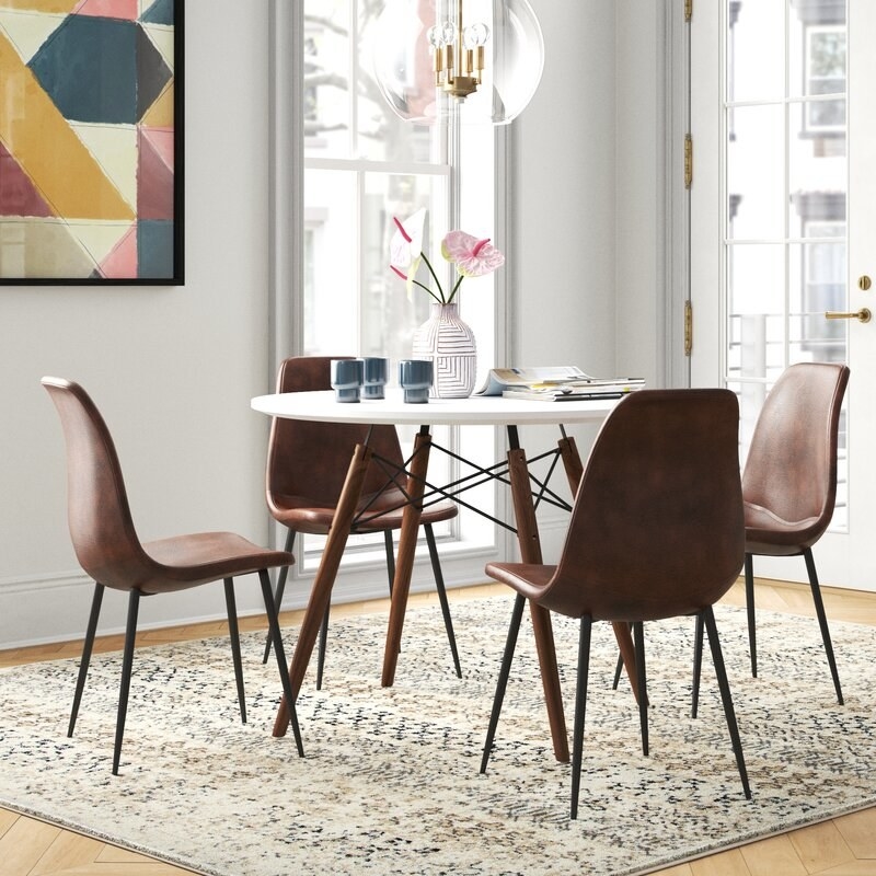 A white and brown dining room table set with four chairs