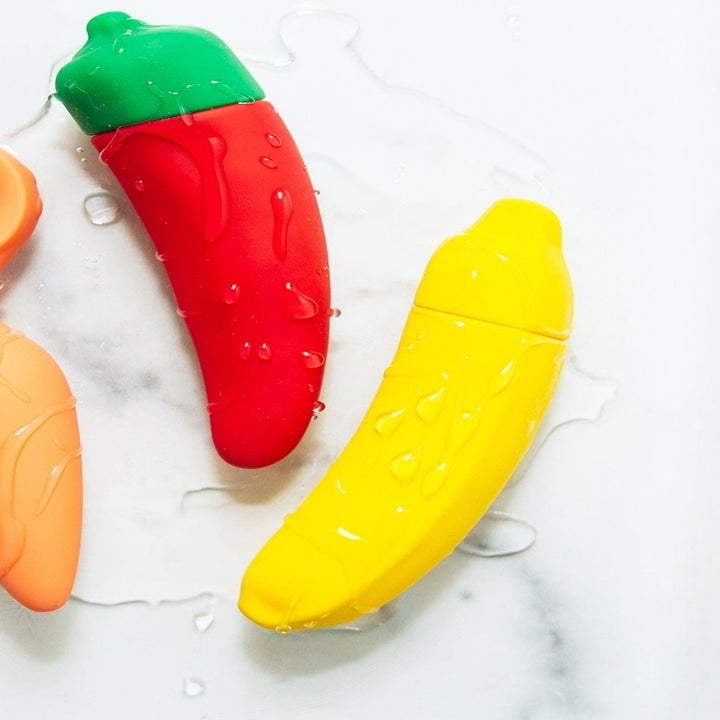 Orange plug, red chili pepper and banana vibrators covered with liquid