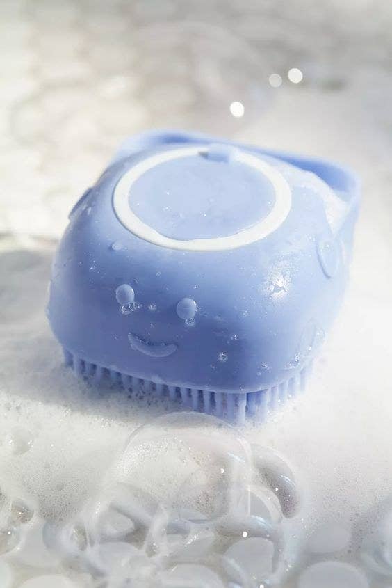the blue scrubber shown all wet and sudsy in a tub
