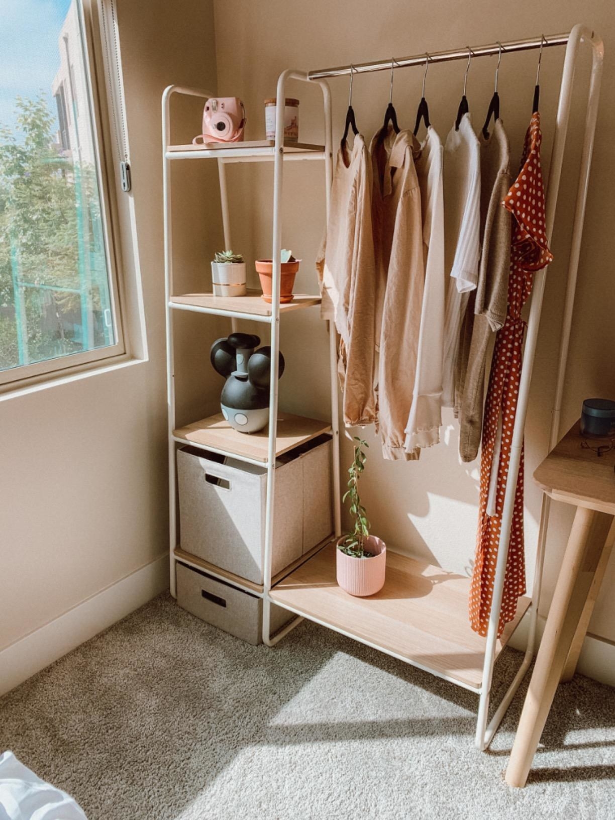 A reviewer&#x27;s white and light wood grain garment rack with shelves