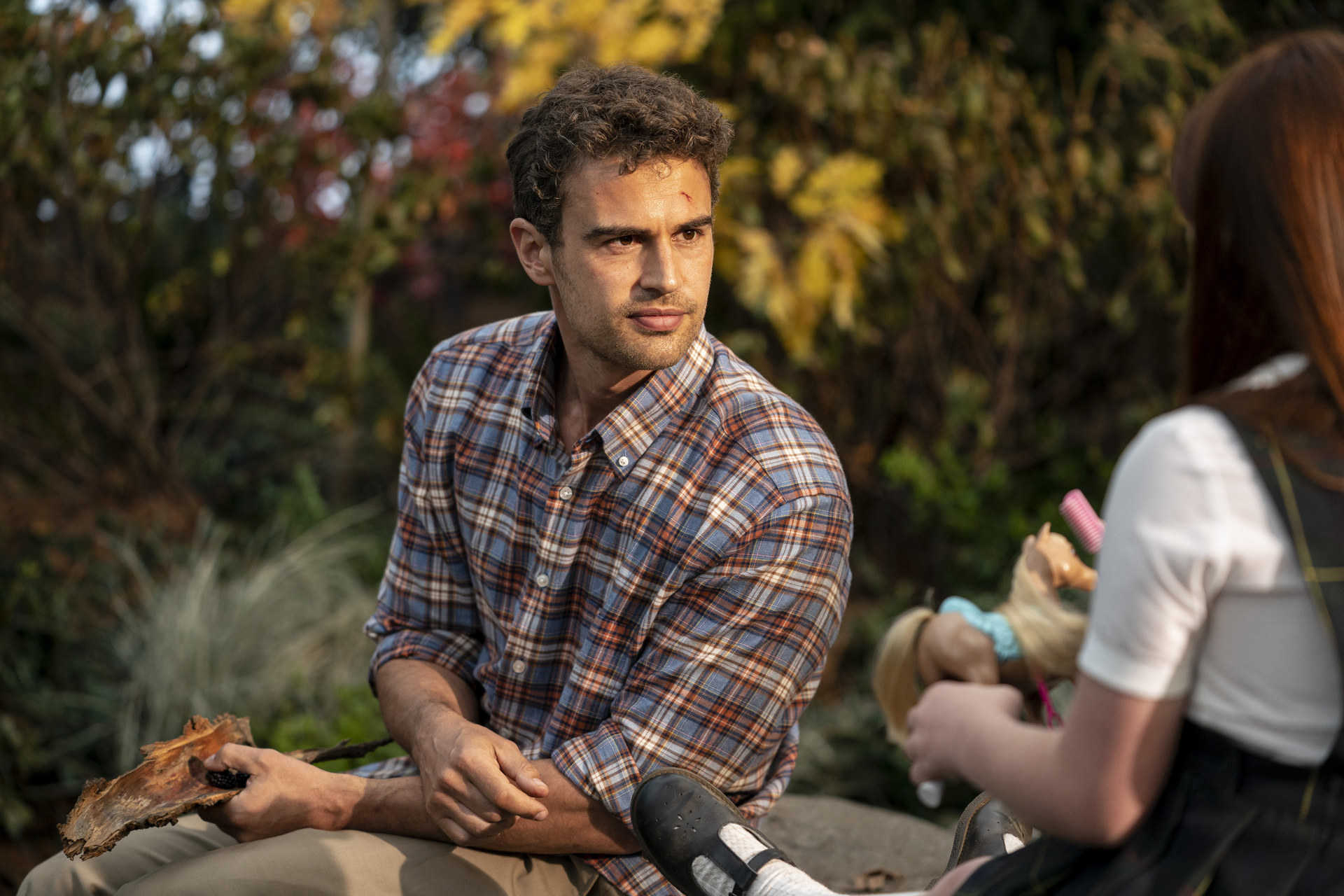 Theo in a plaid shirt staring at Claire, played by Rose