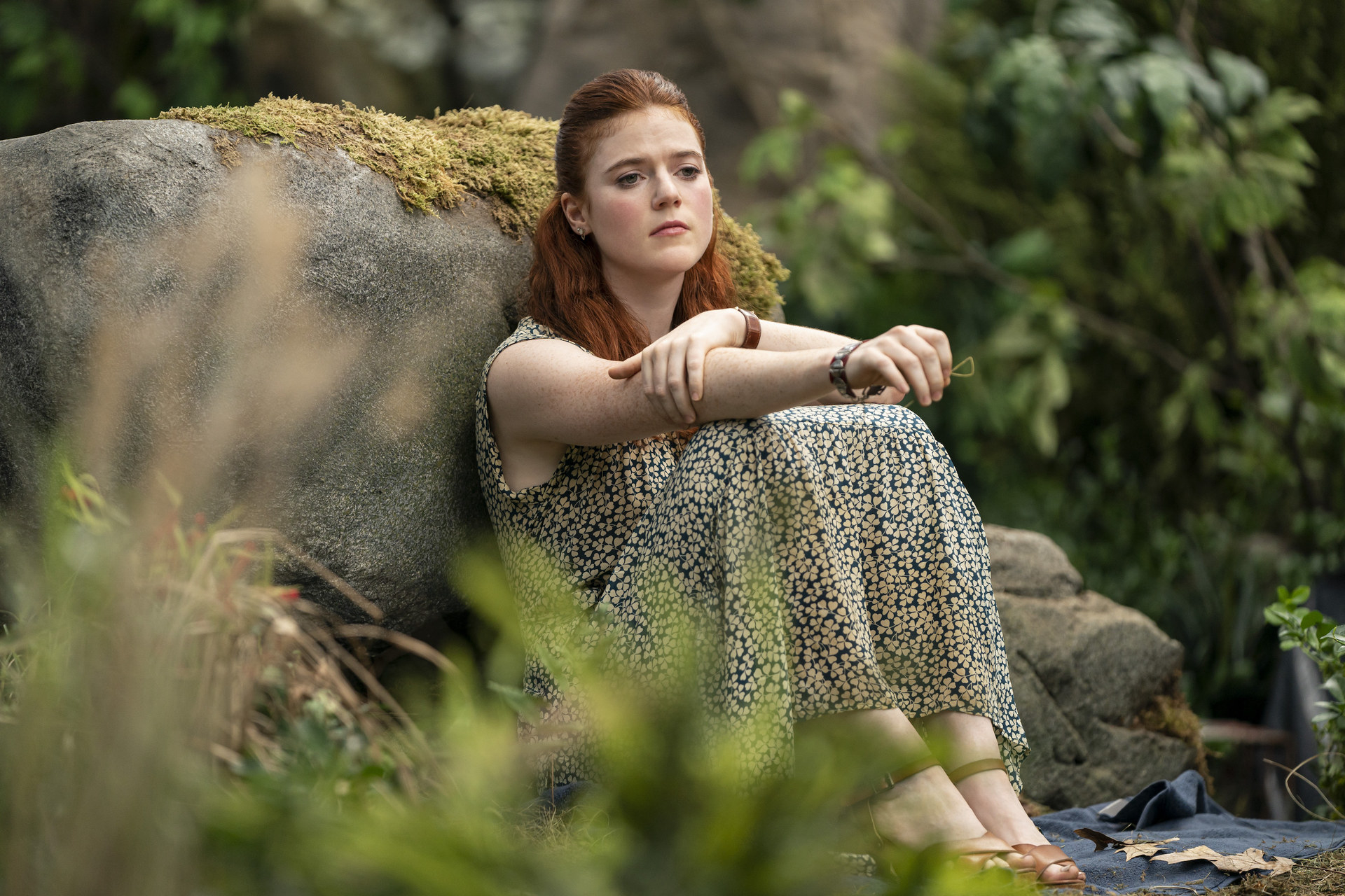 Rose (playing Clare) sitting sadly by a rock