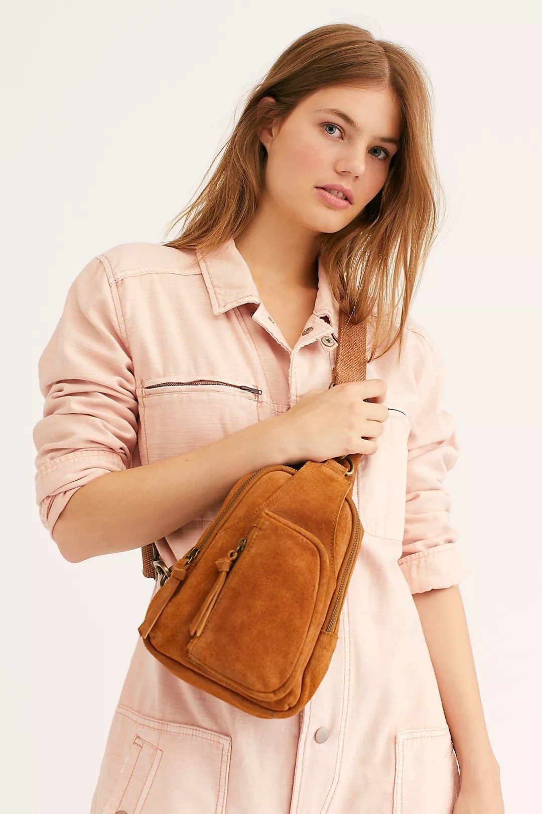 Model wearing camel suede looking bag, with two zippers