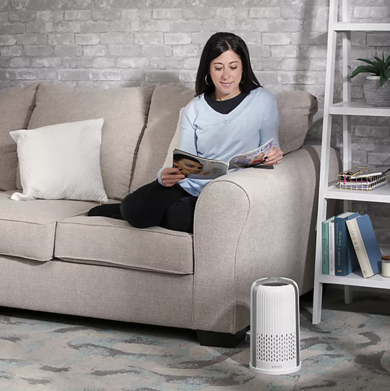 model sitting on the couch with the air purifier on the floor