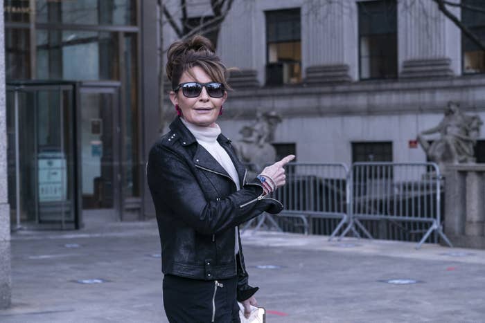 Sarah Palin is pictured wearing sunglasses and a leather jacket and pointing as she leaves court