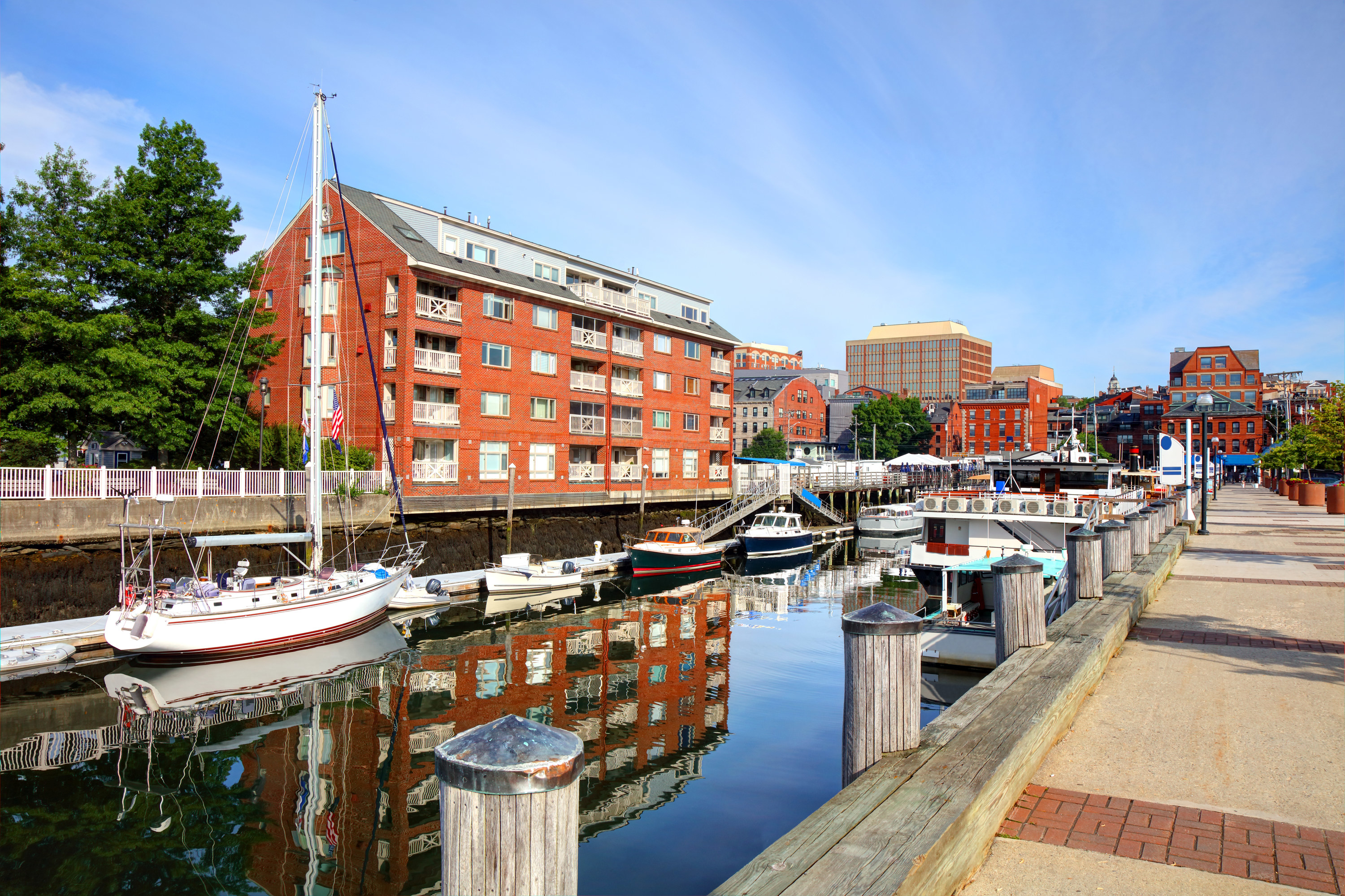 Dock near a canal in portland, lined with different sailboats and near apartment buildings