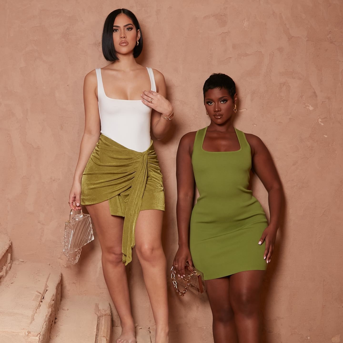 a model wearing a white swimsuit and a green skirt next to a model wearing a green dress