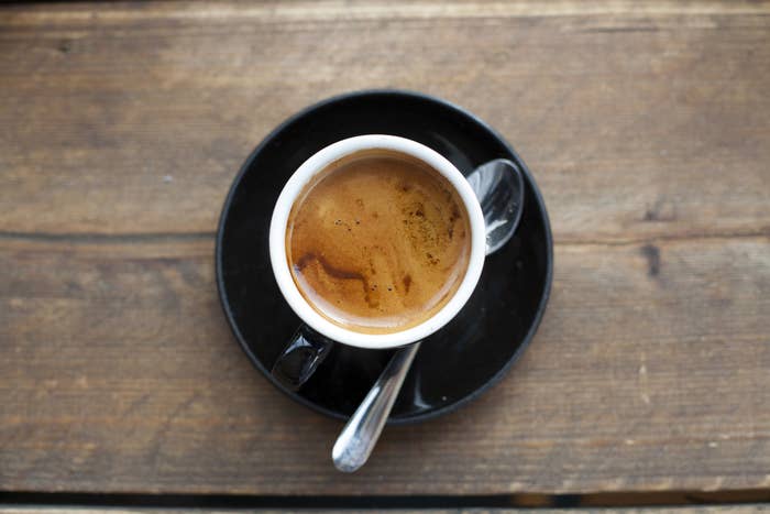 A cup of espresso on a saucer with a spoon
