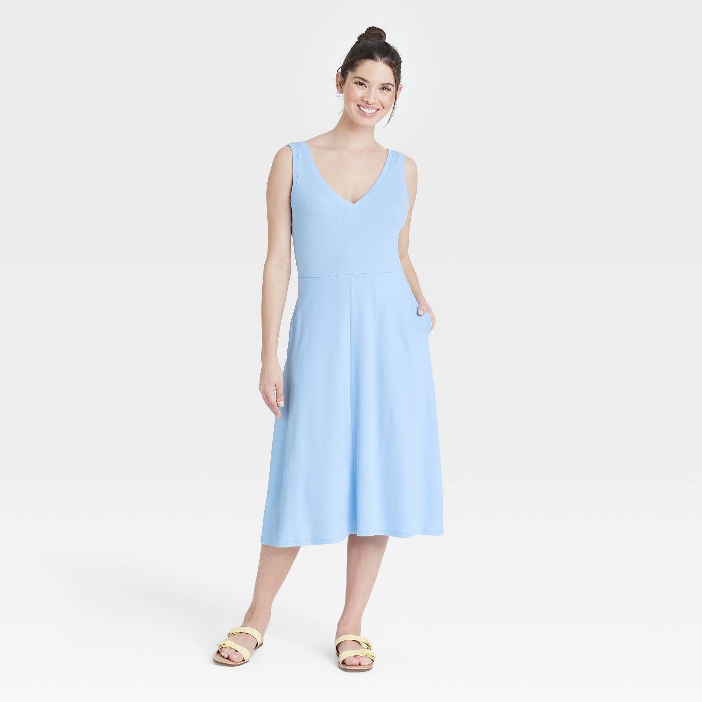Model wearing light blue dress and cream shoes