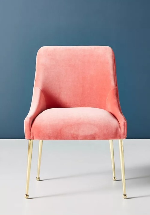 An image of a pink velvet chair with removable polished brass legs