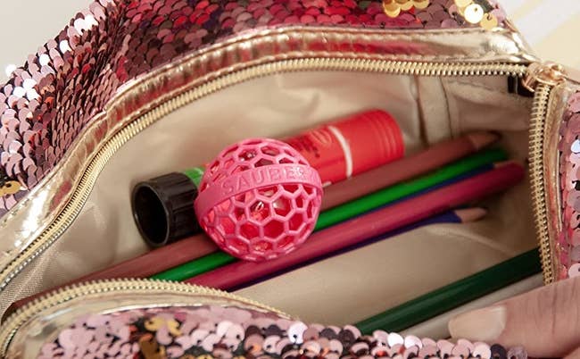 a pink plastic ball in an open purse