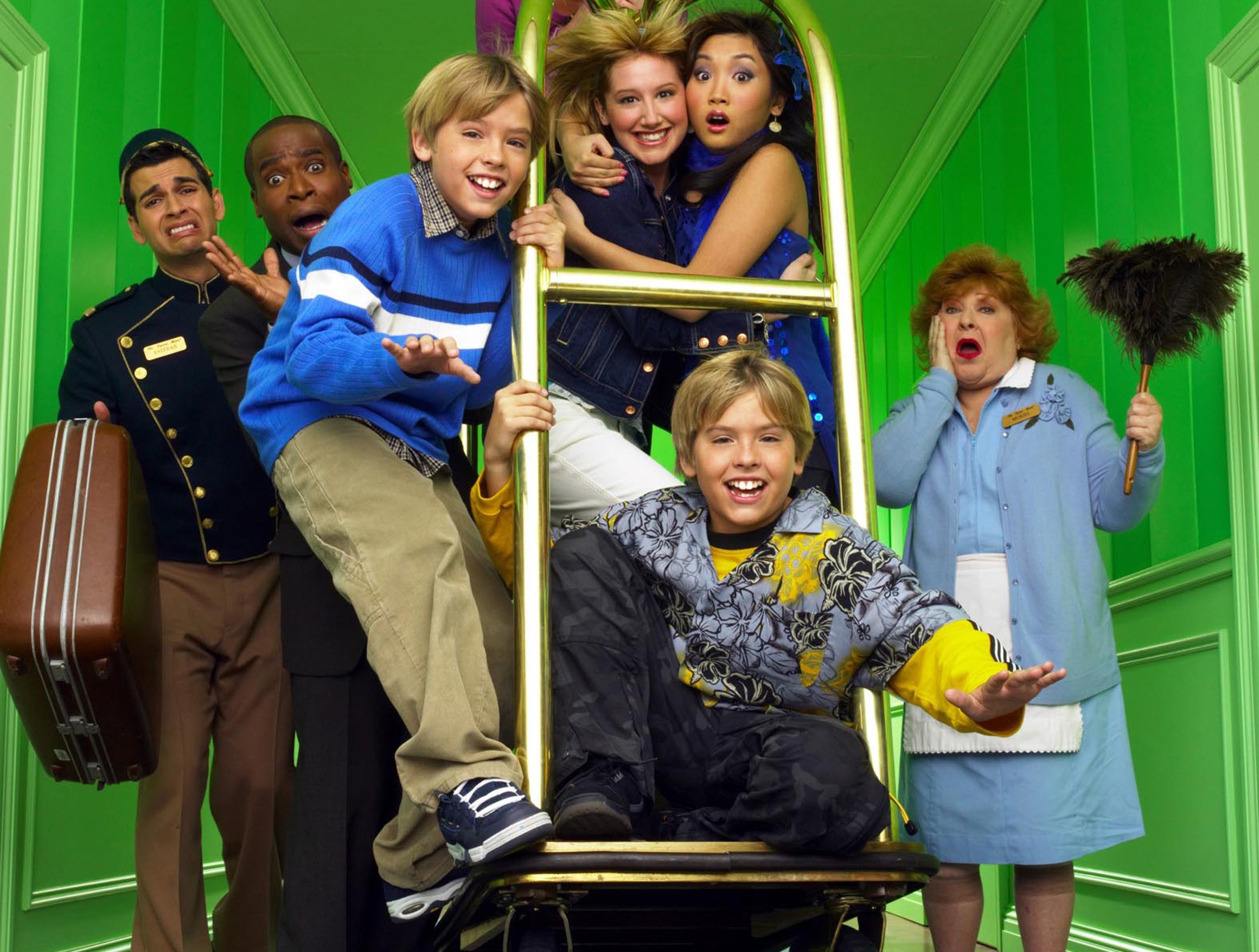 The cast of The Suite Life of Zack and Cody ride on a luggage cart