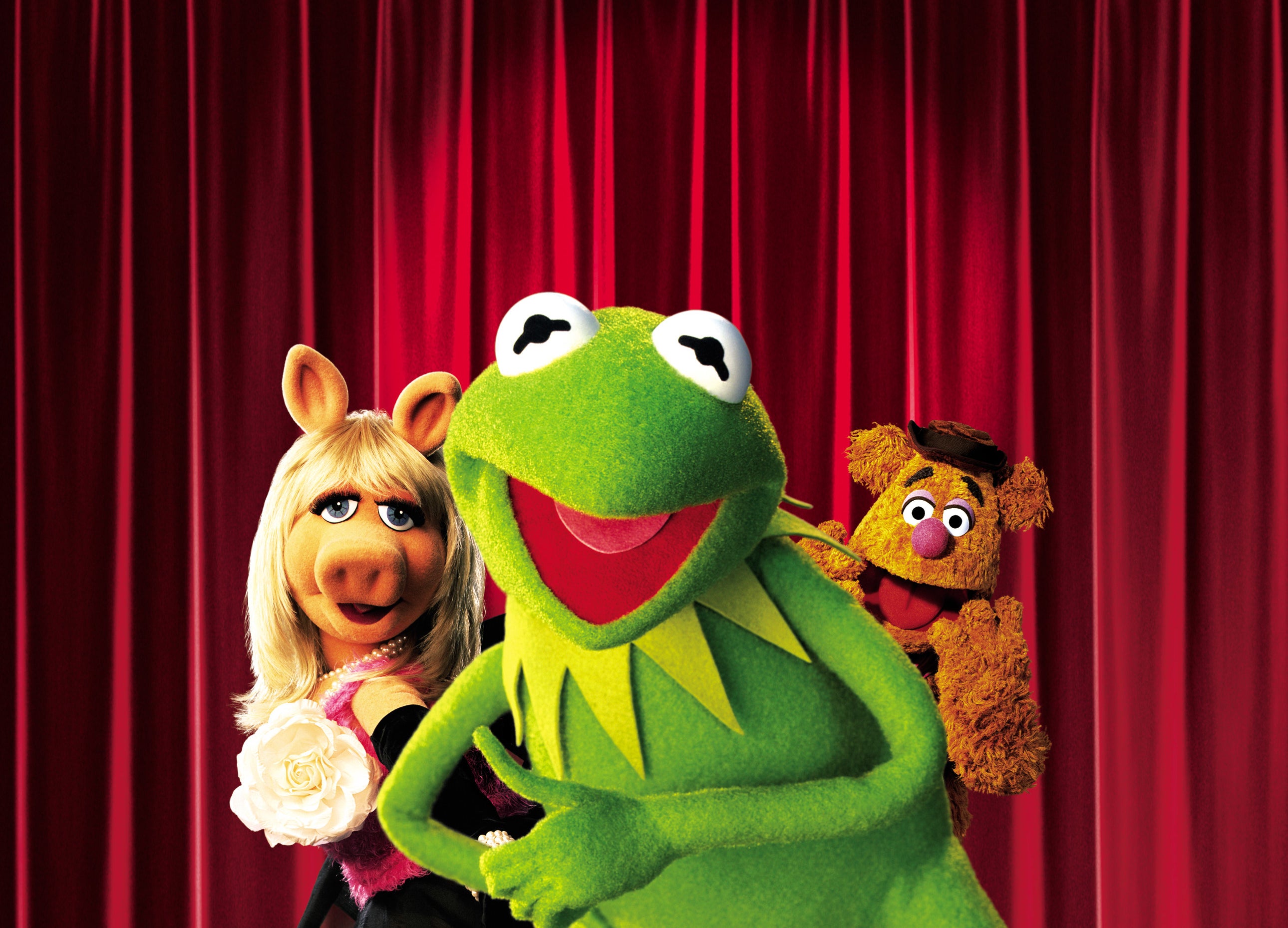 Kermit, Miss Piggy, and Fozzie Bear in front of a curtain