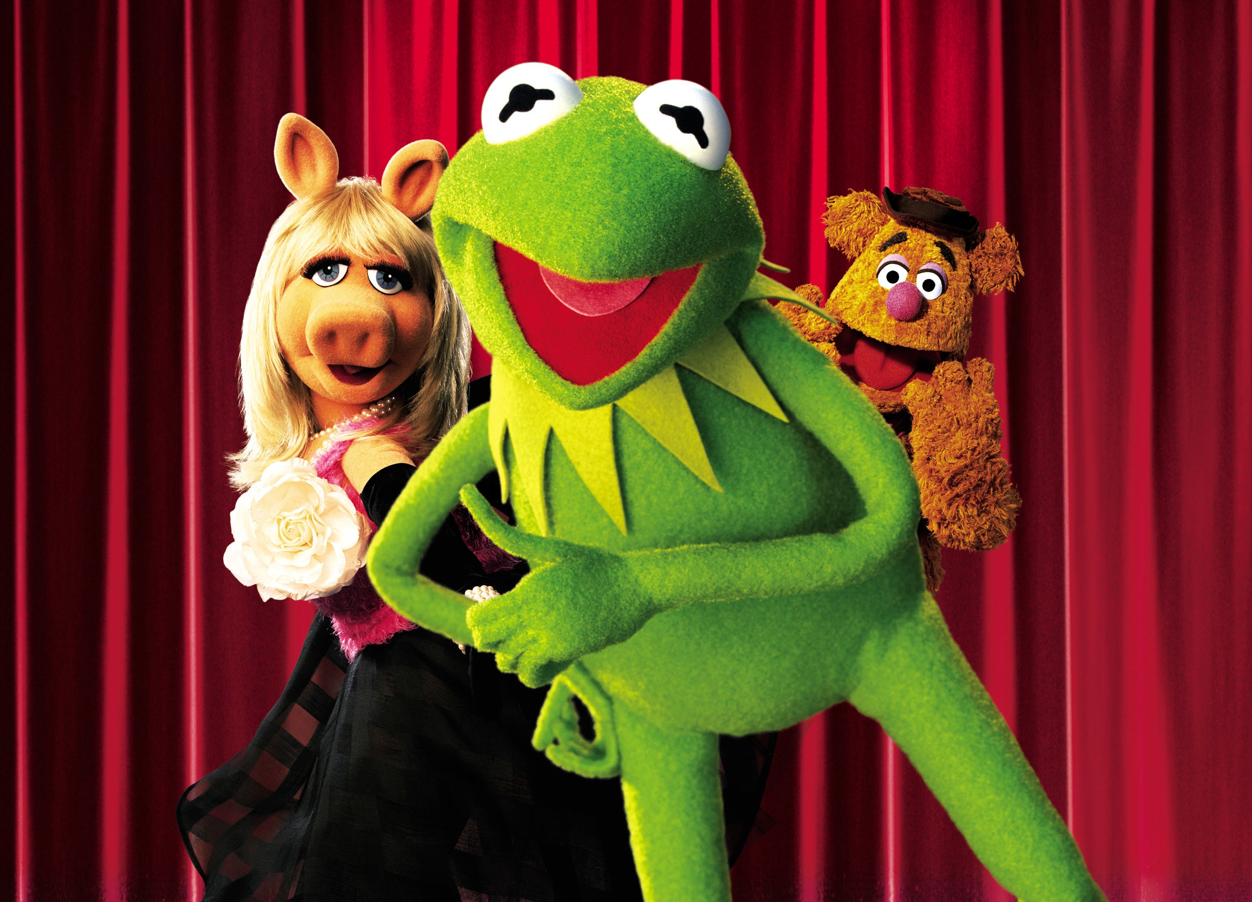 Kermit, Miss Piggy, and Fozzie Bear in front of a curtain