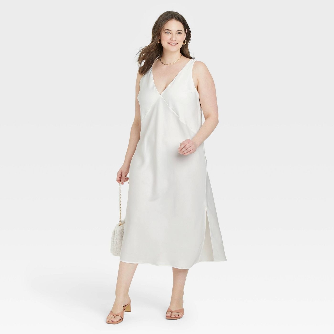 Model wearing white slip dress, white bag and nude shoes