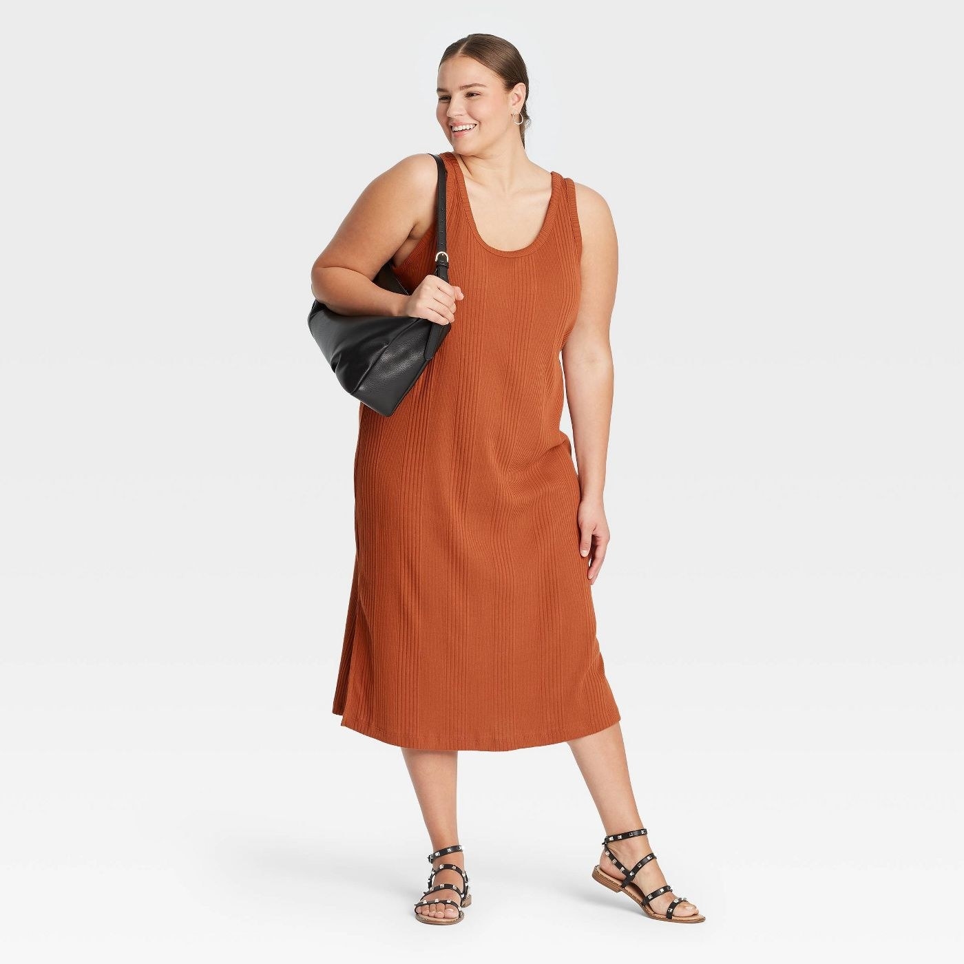 Model wearing rust color dress with large bag and black shoes