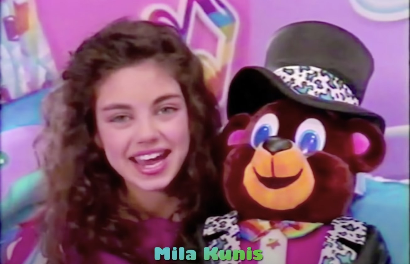 Mila Kunis holding a teddy bear in a Lisa Frank commercial