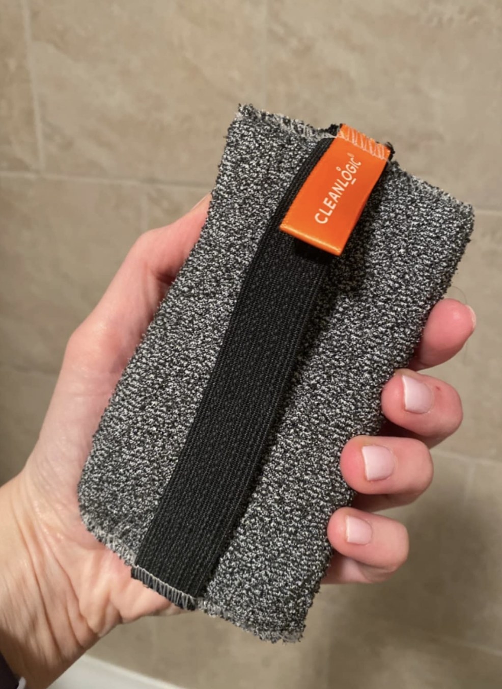 a reviewer holding the charcoal body scrubber