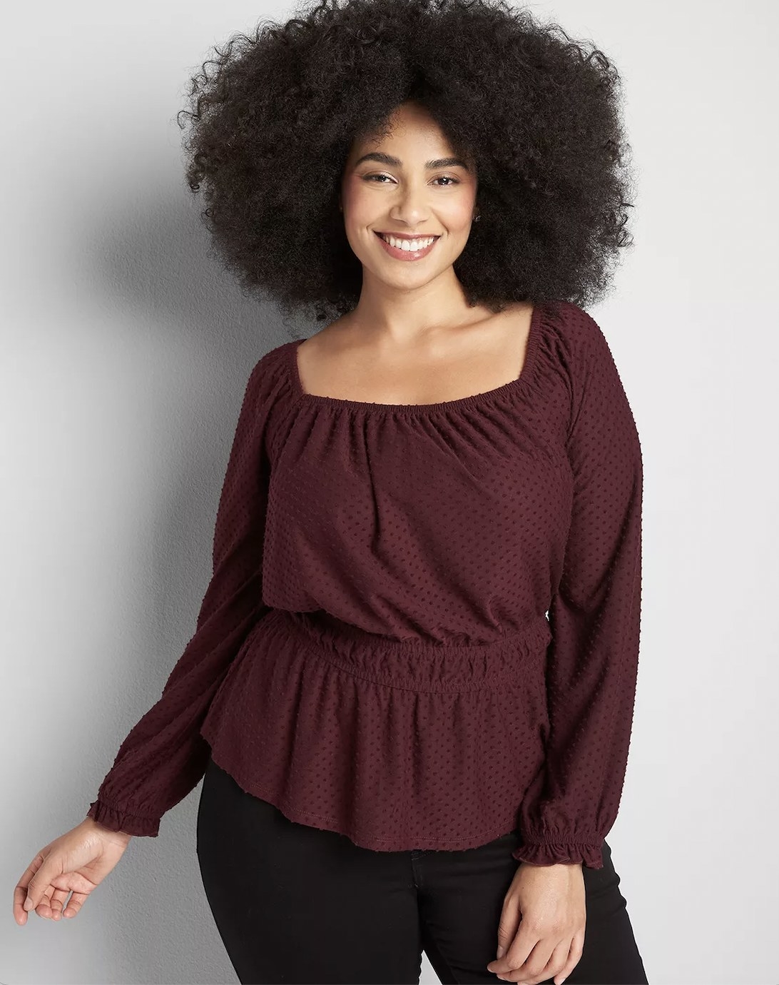 A person wearing a burgundy square-neck top