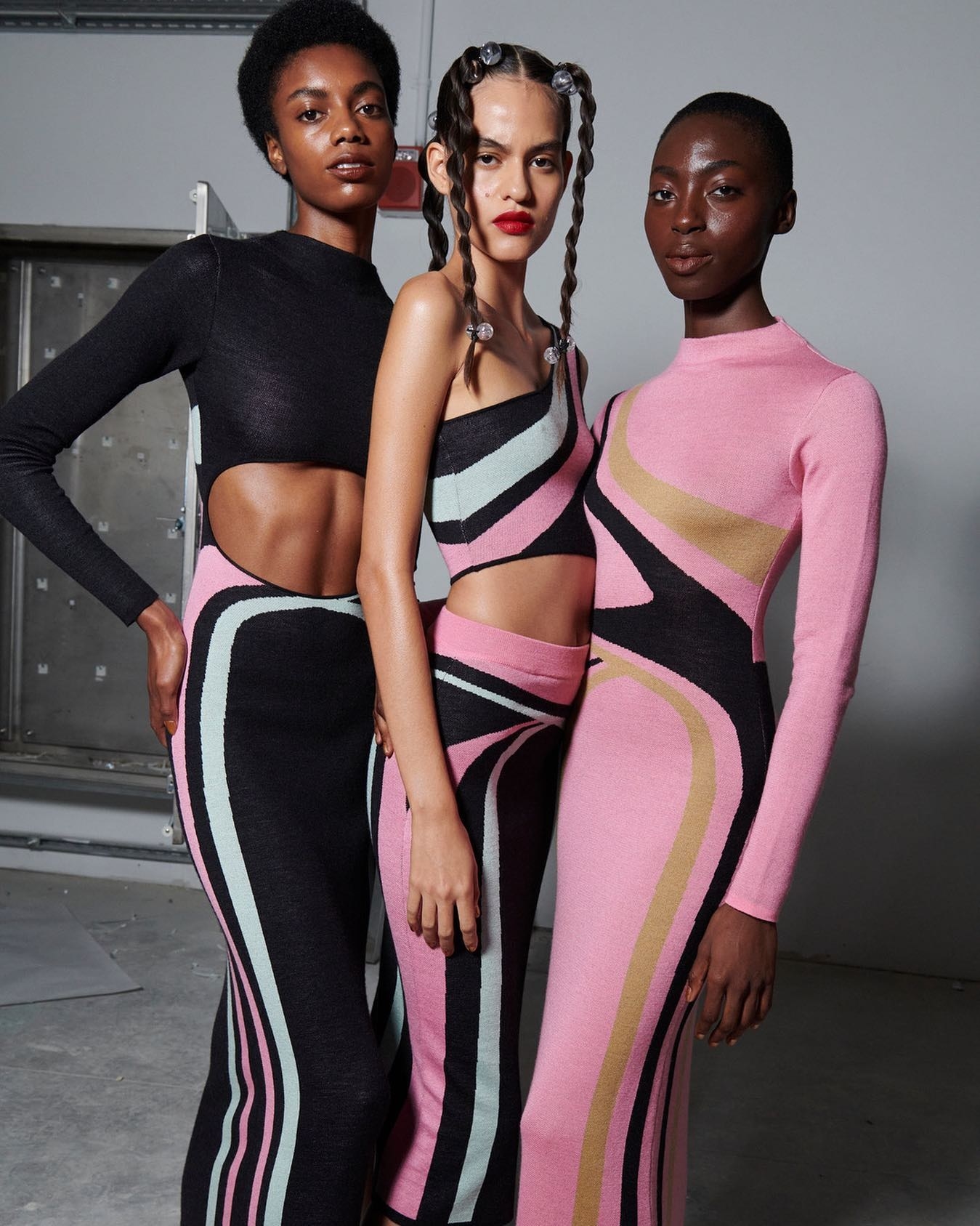 three model dressed in pink, black, and baby blue knit outfits
