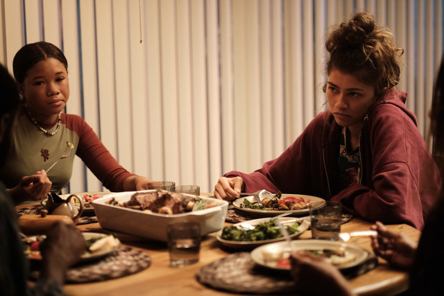 Two sisters sit at a dining room table. 