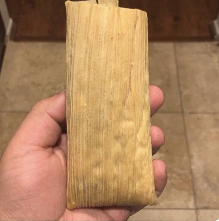 Me holding a tamal in its corn husk