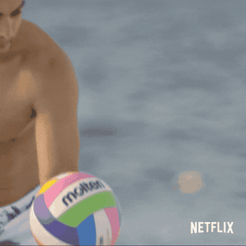 Sal underhand serving a colorful volleyball on the beach