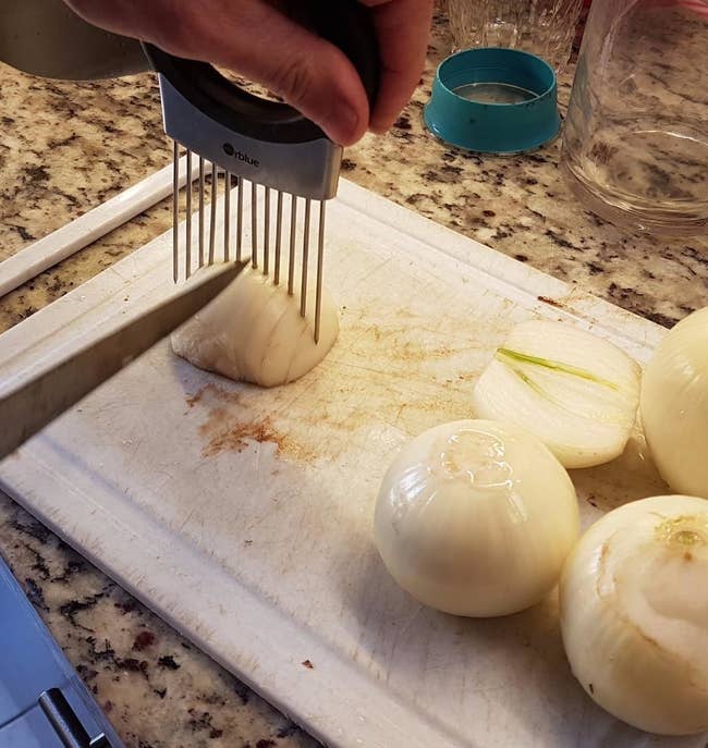 a reviewer chopping an onion held in place by the stainless steel holder