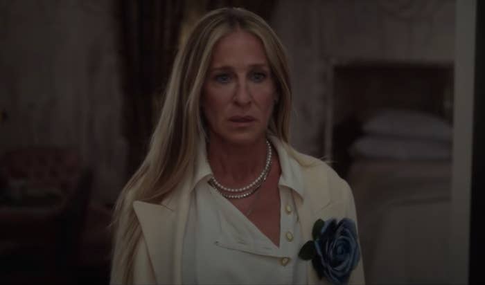 Carrie blankly stares towards where Big is laying in the shower