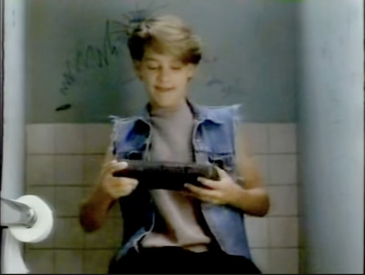 Tobey Maguire playing a video game in a restroom in an Atari Lynx commercial