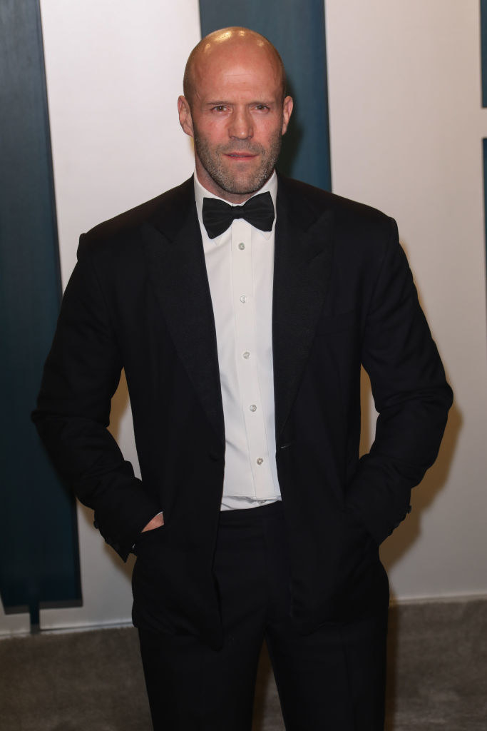 dress in a classic tux and bowtie, the bald actor poses with his hands in his pockets