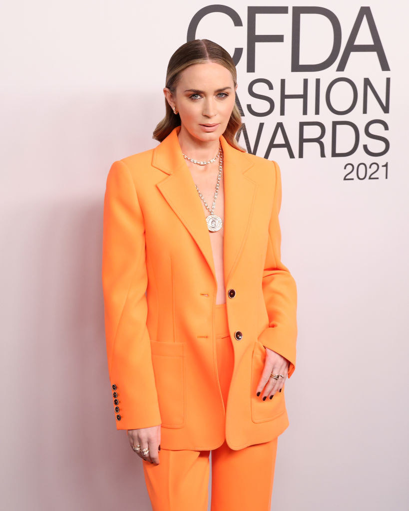 dressed in a bold suit with an open jacket in place of a top, the actor poses with her hand in her pocket on the red carpet