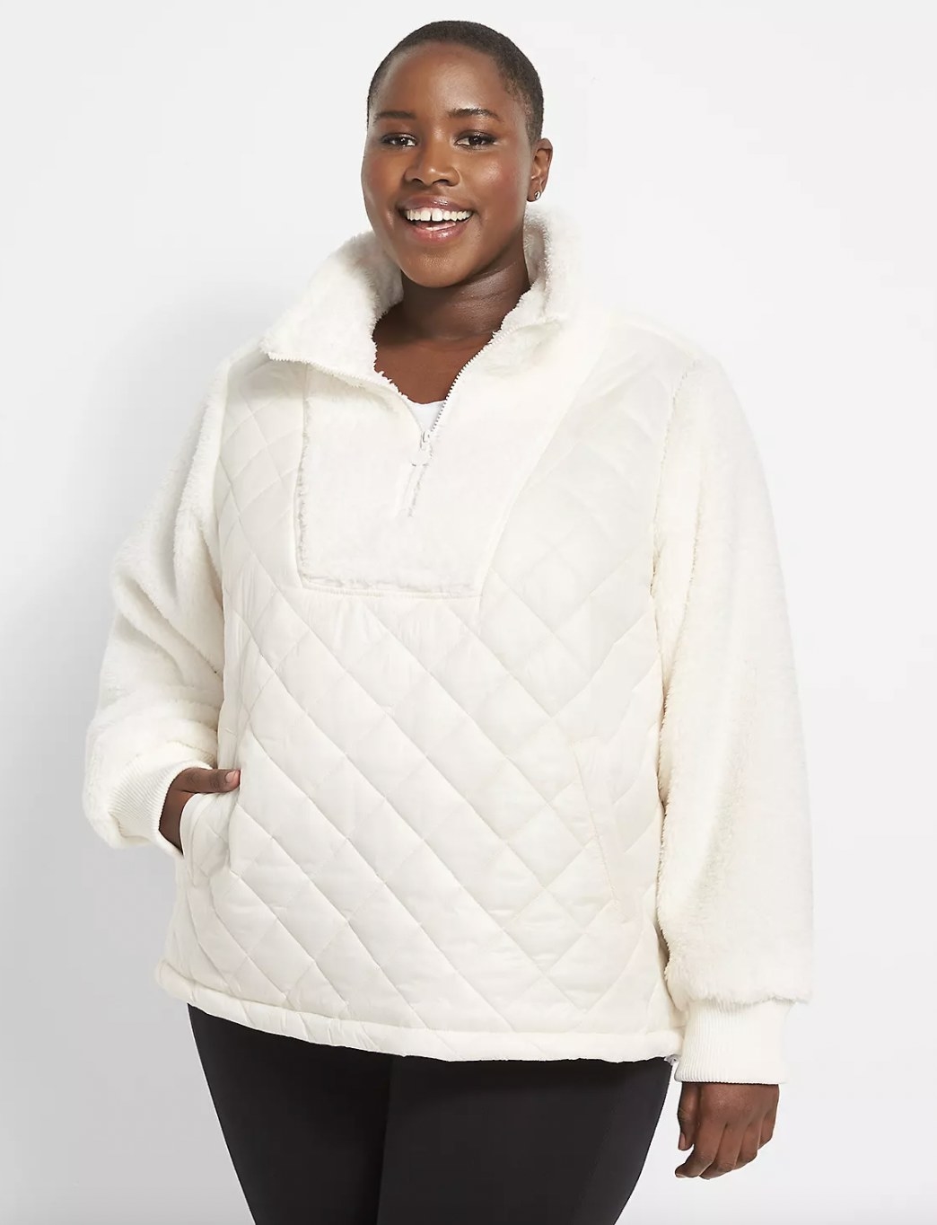 A person wearing a cream sherpa with black leggings