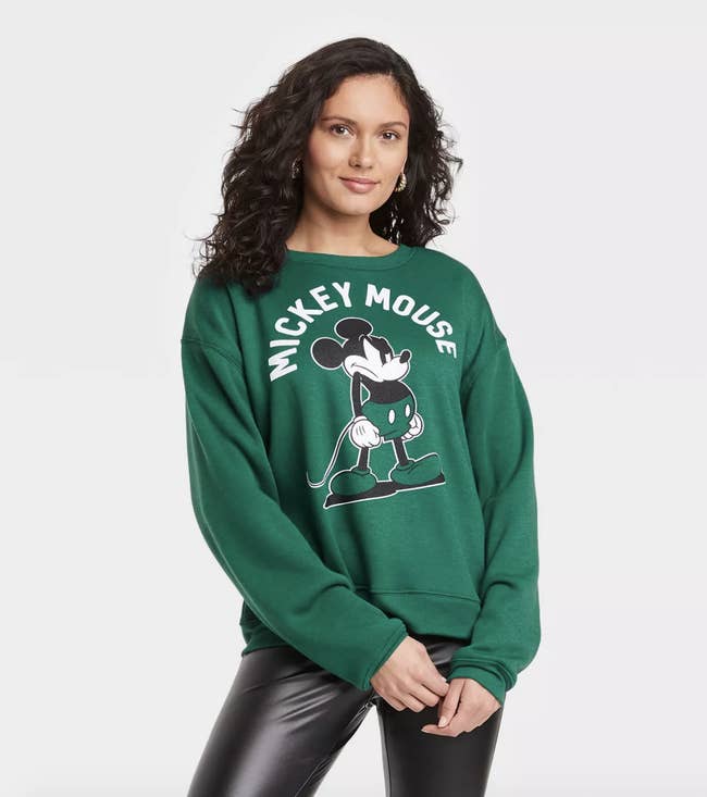 a moden in a dark green sweatshirt with a grump image of mickey mouse on it