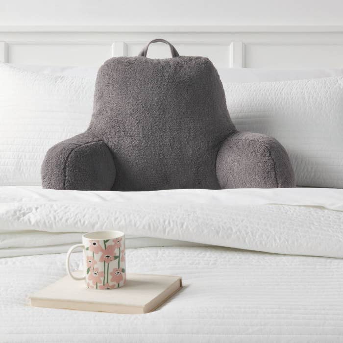 A grey fleece bed rest pillow