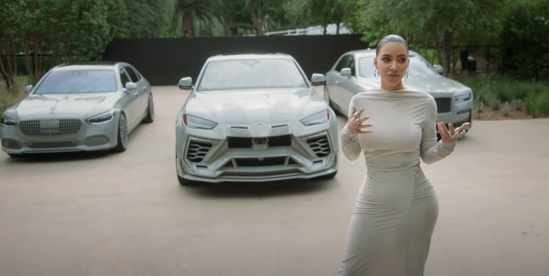 Kim standing in front of her three grey cars
