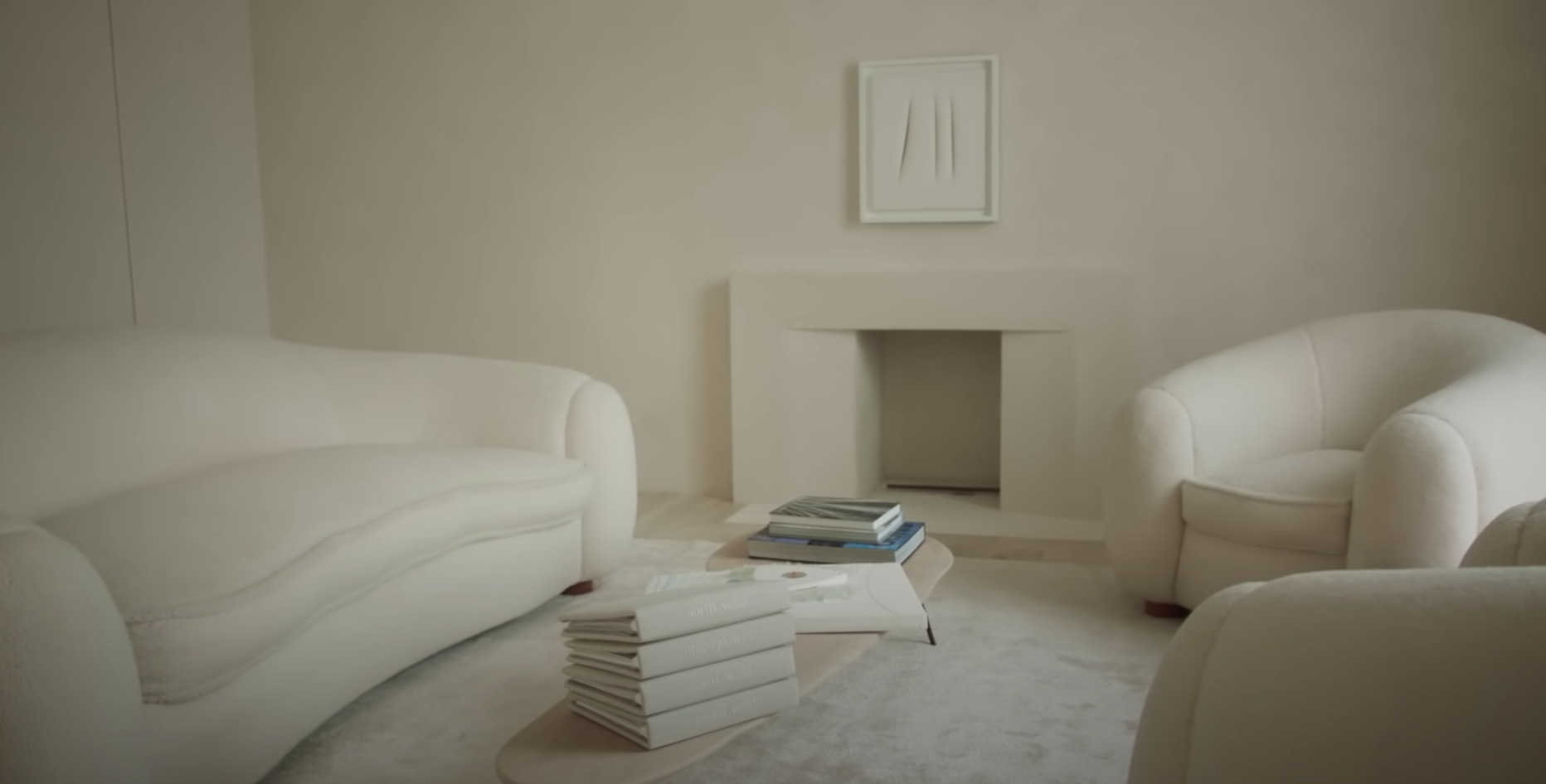 living room space with new artwork, slim coffee table, books, and cream seating