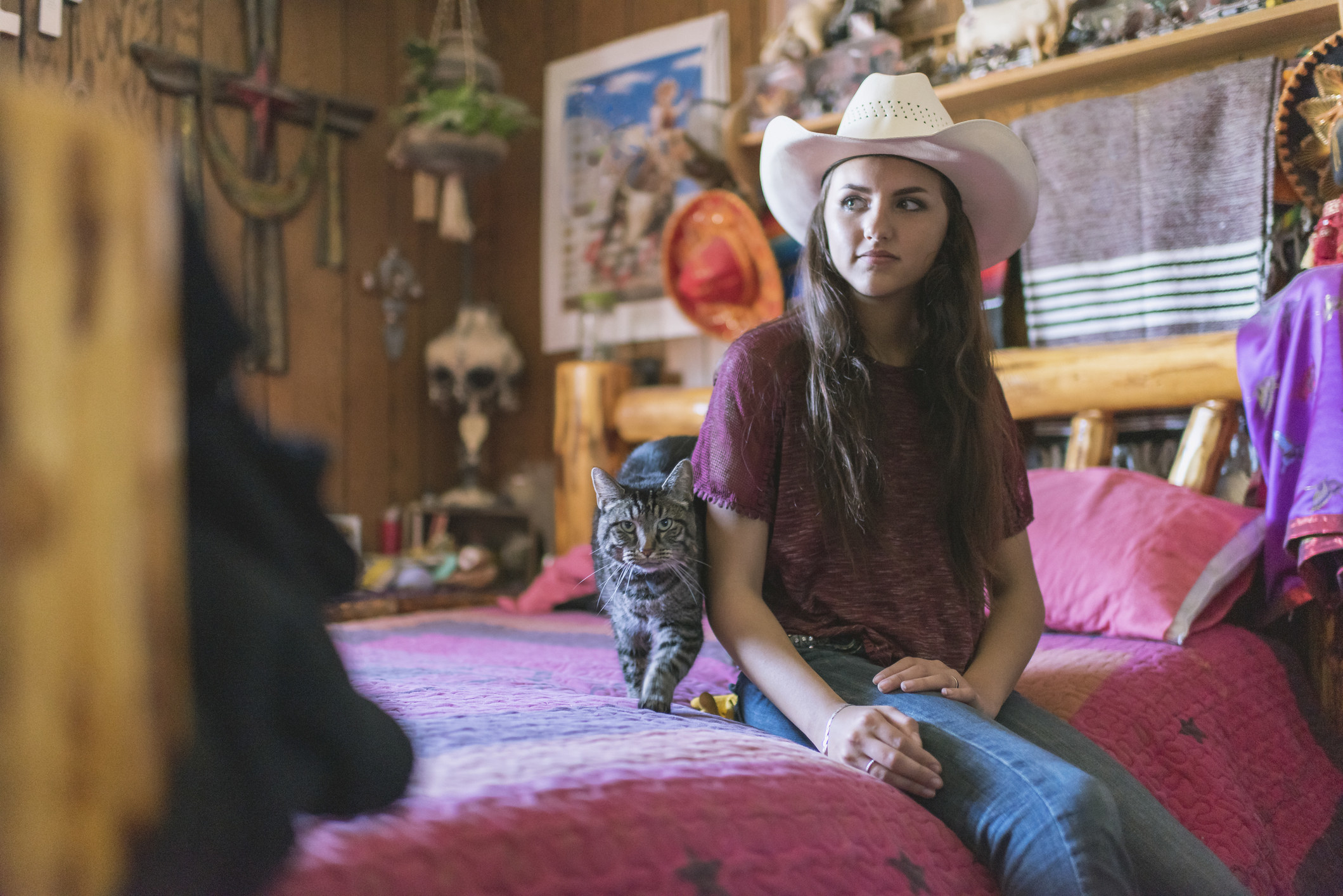 a cat on the bed with a women in a cowboy hat