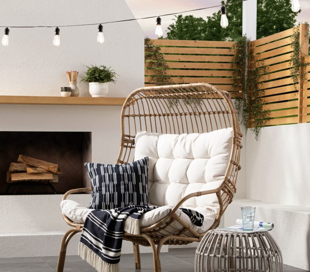 The woven dark brown chair frame has a white cushioned pillow and is in an outdoor patio