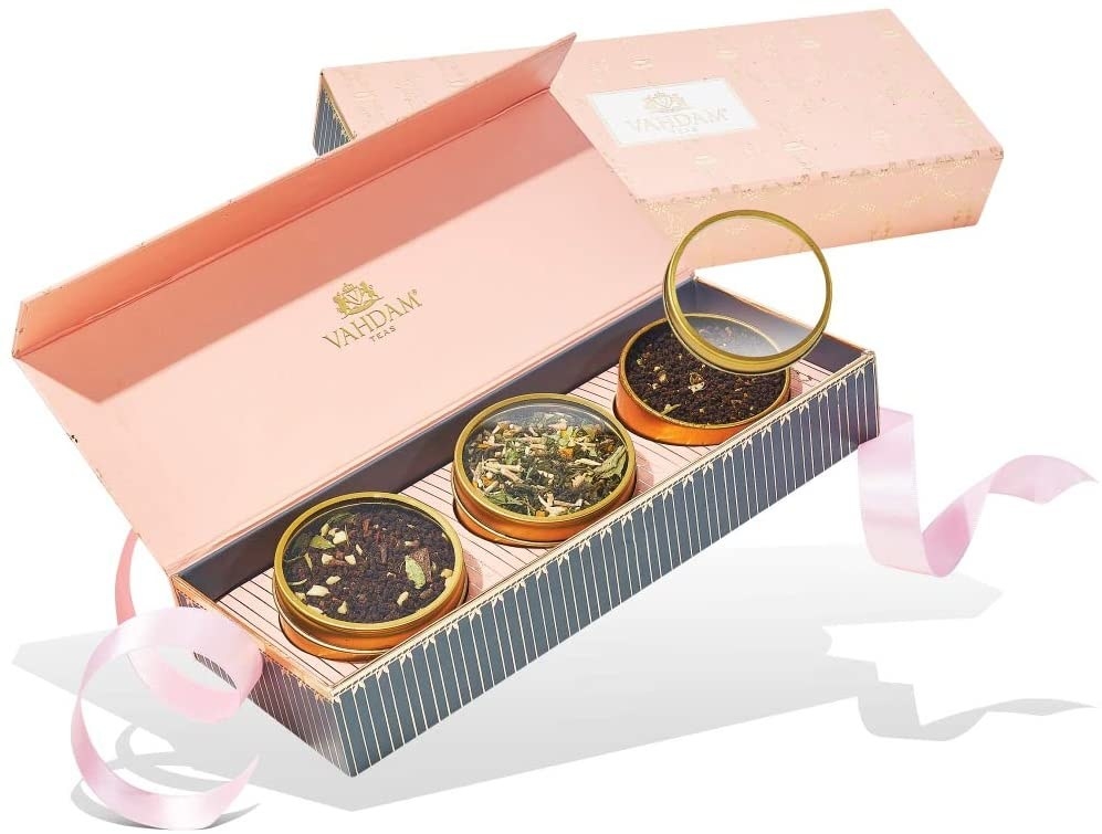 a tea gift set with three different circular tea tins inside