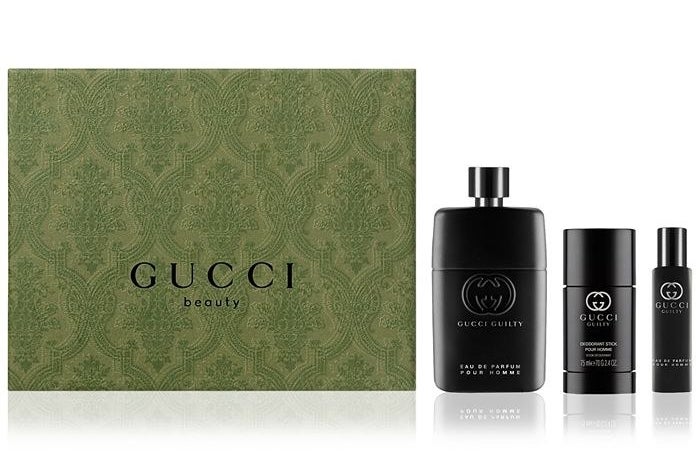 Three black bottles of the fragrance next to the green Gucci gift box