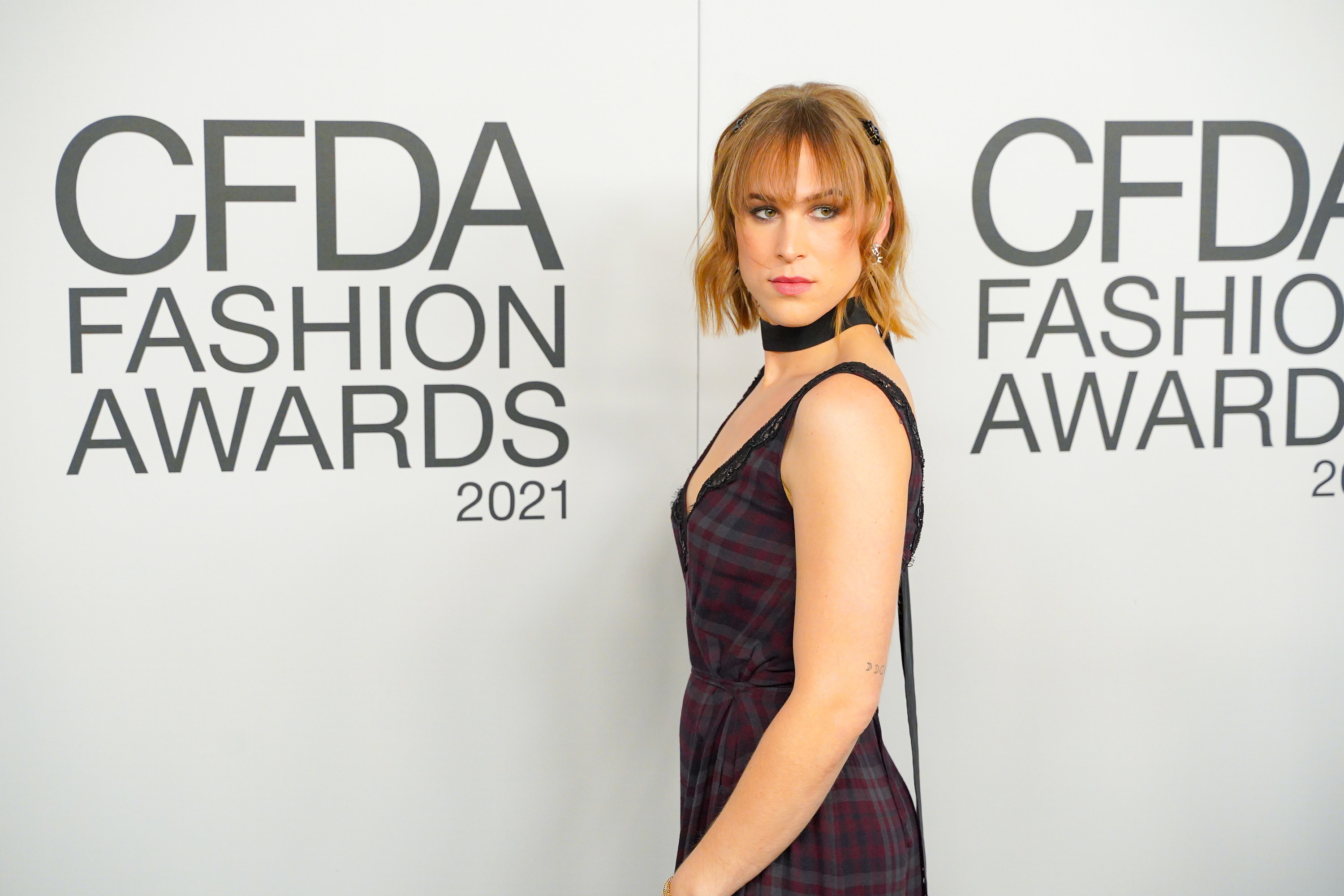 Tommy looks over her shoulder as she poses on the red carpet of the 2021 CFDA Fashion Awards