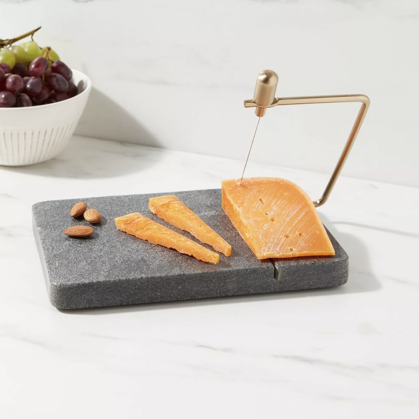 The grey marble cheese platter being used to slice a block of cheese