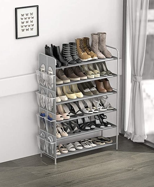 The shoe rack filled with different shoes against the wall of a trendy room next to a window