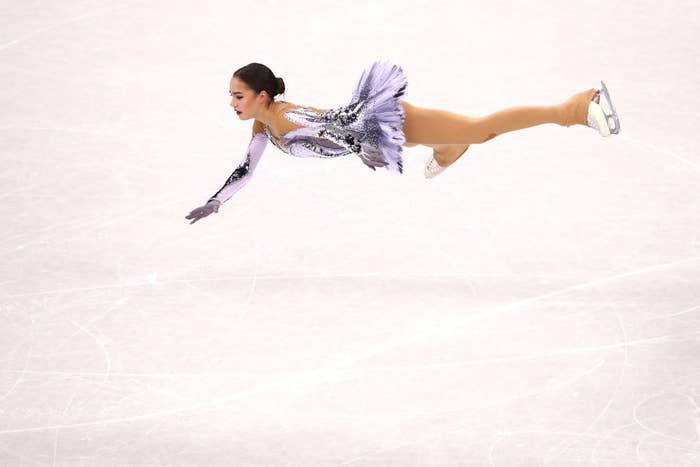 an ice skater completes a jump in mid-air