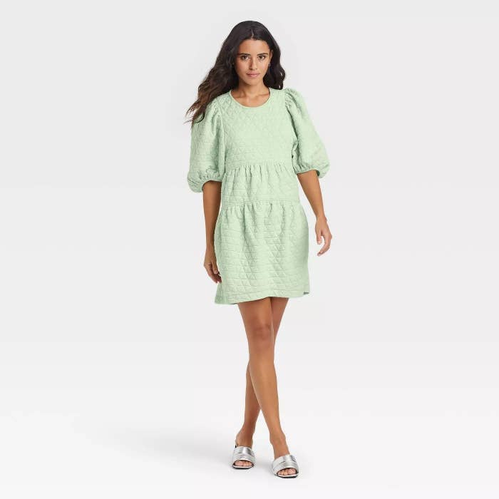 Model wearing dress with 3/4 sleeves, stops mid thigh
