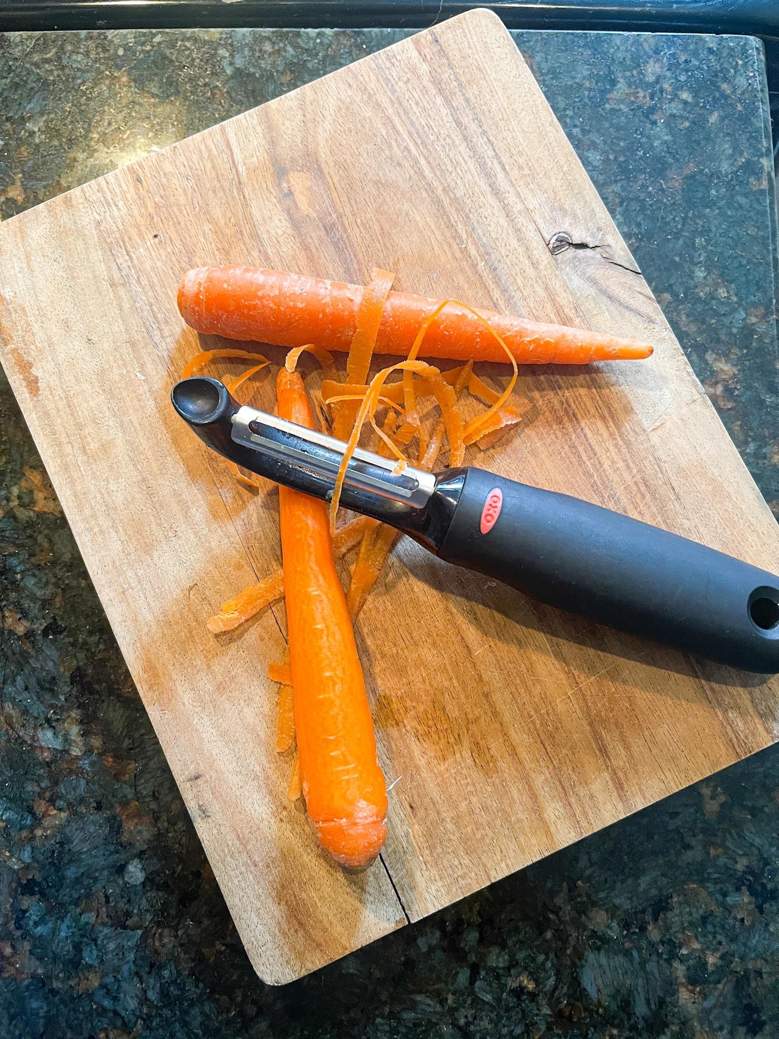 Vegetable peeler peeling two carrots